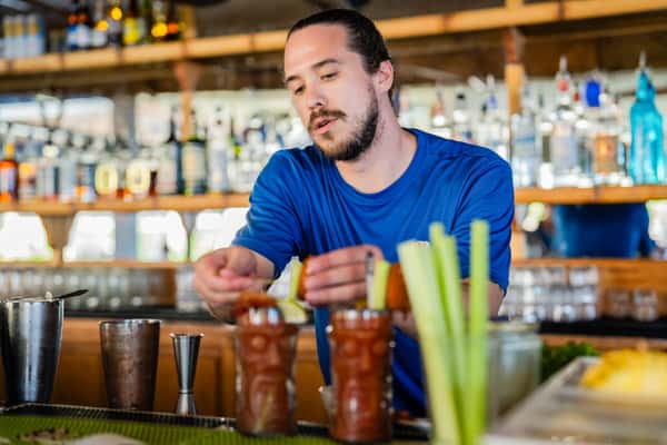 bartender preparing cocktails with fresh ingredients behind a busy restaurant bar