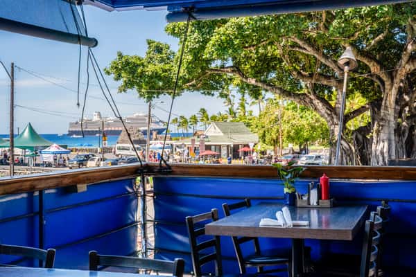 Outdoor waterfront patio seating with blue decor and scenic marina views at a vibrant coastal dining destination