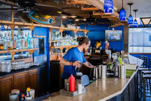 restaurant staff member preparing drinks behind a busy bar in a lively casual dining environment