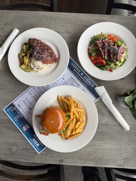 Assorted gourmet burgers and loaded fries served at a modern waterfront restaurant with upscale casual dining atmosphere