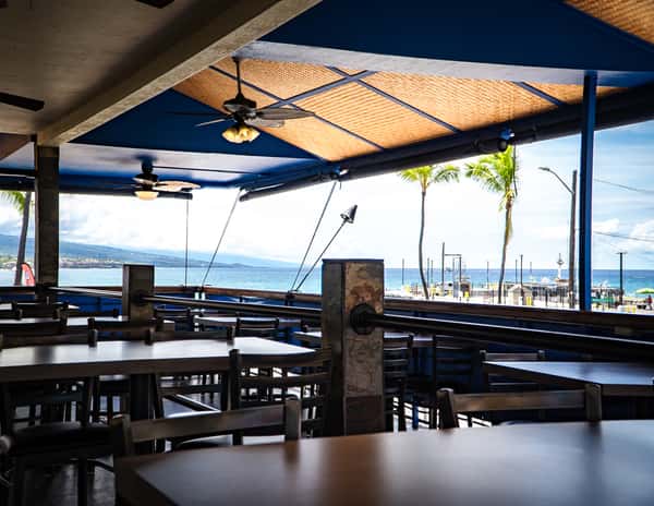 Open-air waterfront dining area with bar seating and marina views creating a relaxed coastal restaurant atmosphere