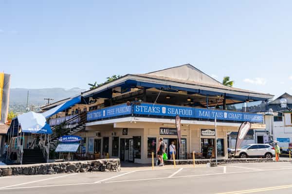 corner view of a busy beachside restaurant with outdoor patio seating in a sunny coastal setting