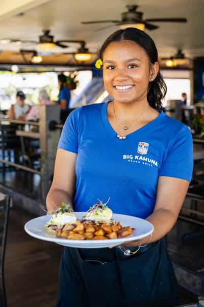 restaurant server holding a plated seafood dish in a bright and welcoming restaurant dining area