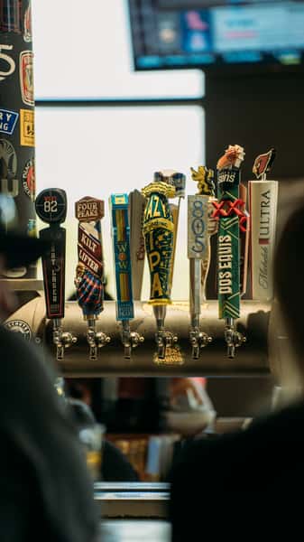 Close-up of beer taps at a bar featuring Guinness, Voodoo Ranger, Lagunitas, Modelo, and other craft beers, perfect for draft beer lovers.