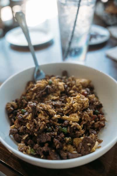 Hearty bowl of beef fried rice with scrambled eggs, green peas, and savory seasoning, served fresh for a flavorful comfort meal.