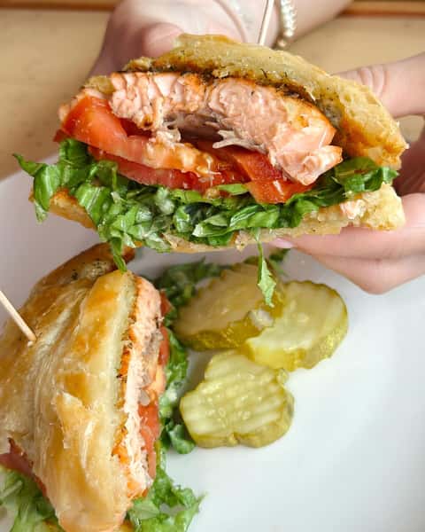 Fish burger with a side of pickle slices