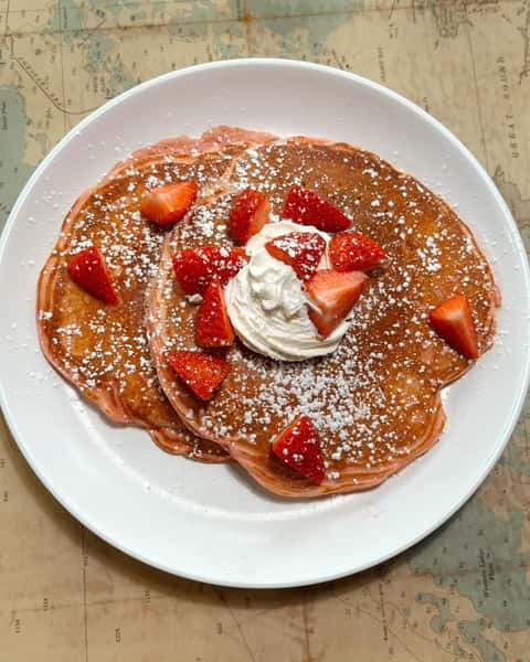 Pancakes and cream with strawberry slices