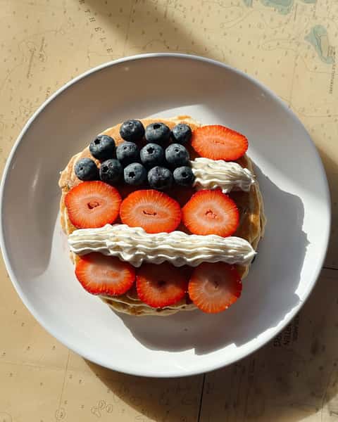 Stacked pancakes and cream with strawberry slices