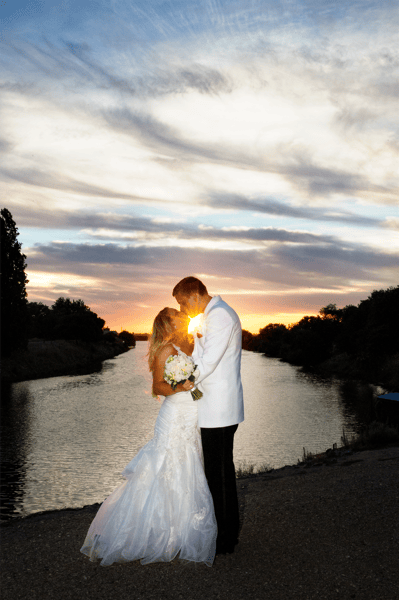 bride and groom in front of sunset