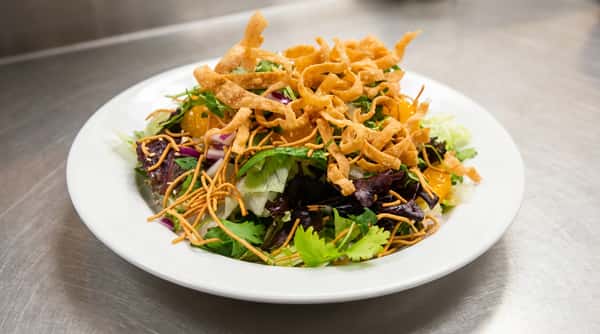 Asian salad with mixed greens, mandarin oranges, purple onion, fried wonton strips, chow mein noodles, and sesame seeds.