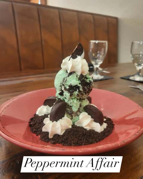 Mint chocolate chip ice cream topped with whipped cream and peppermint patties, served over a bed of chocolate cookie crumbs.