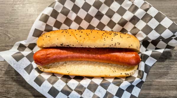 Hot dog in a poppy seed bun, wrapped in black and white checkered paper.
