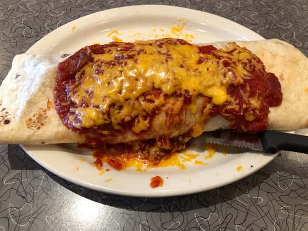 a breakfast burrito covered in red sauce and cheese