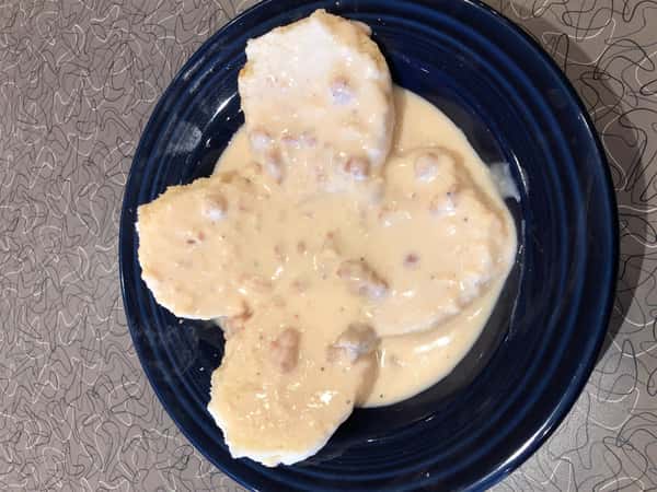 four biscuits on a plate covered in gravy