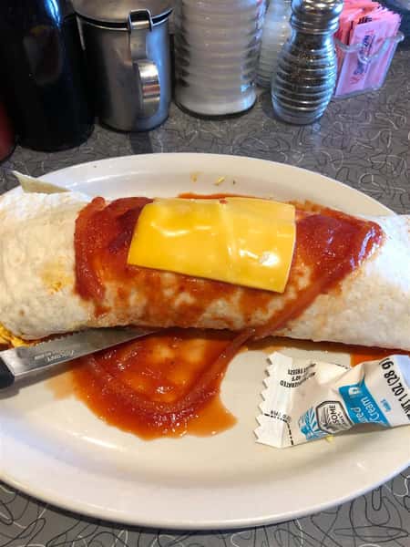 a breakfast burrito covered in red sauce and an american cheese slice on a plate