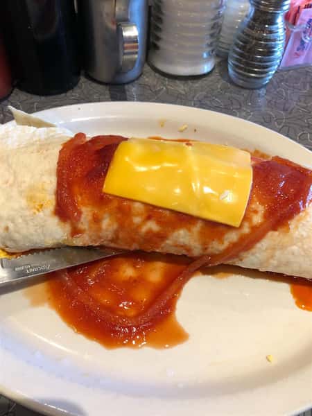 a breakfast burrito covered in red sauce and an american cheese slice on a plate