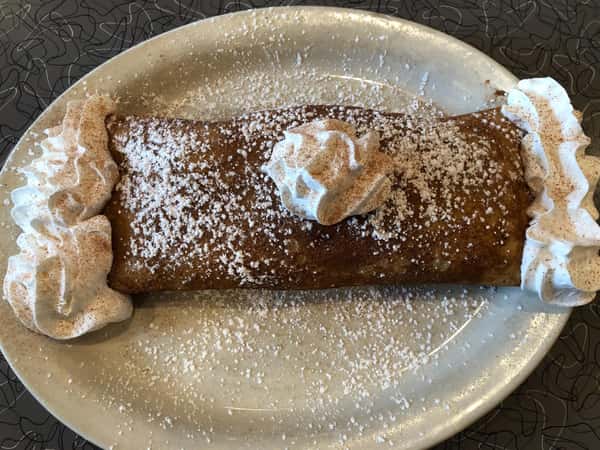 a breakfast crepe covered in whipped cream and powdered sugar