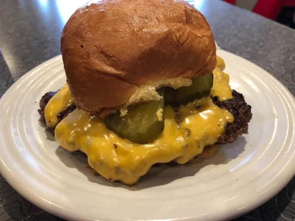 a cheeseburger with pickles on a plate