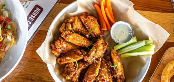 A basket of crispy chicken wings with dipping sauce.