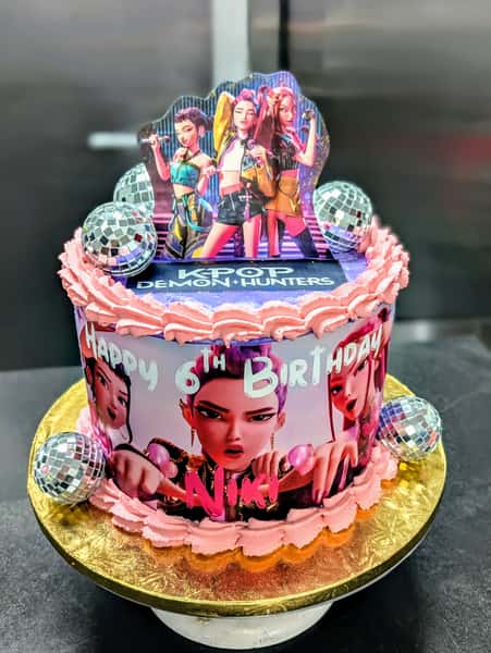 K-pop Demon Hunters themed birthday cake with disco balls and animated characters celebrating Niki's 6th birthday.