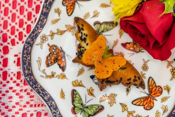 Savory butterfly-shaped pastry topped with a carrot butterfly cutout and black sesame seeds, served on a butterfly-patterned plate.