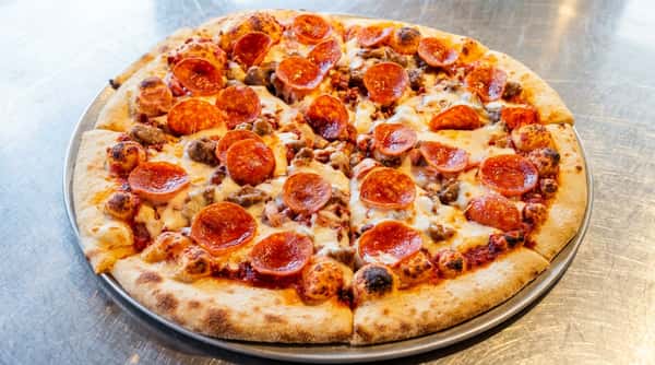 Pepperoni and sausage pizza with melted mozzarella cheese and golden-brown crust on a metal pan.