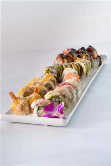 Sushi platter with a plethora of different sushi rolls served with a flower garnish