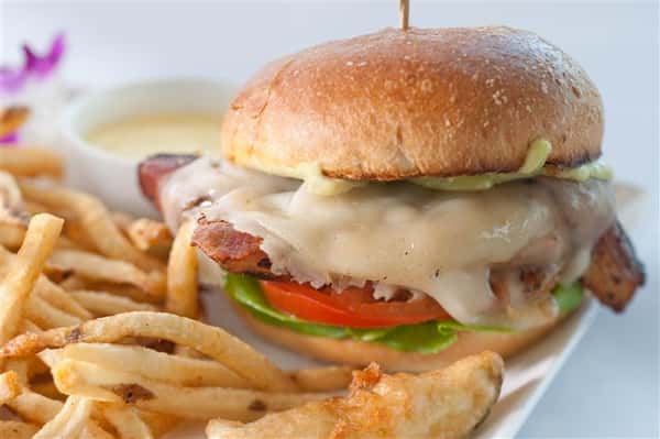 Burger with melted cheese, lettuce, and tomatoes. Served with French fries and dipping sauce