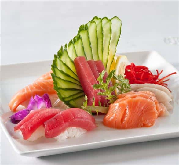 Sushi platter with a variety of different sushi served along with even cut veggies