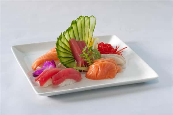 Sushi platter with a variety of different sushi served along with even cut veggies