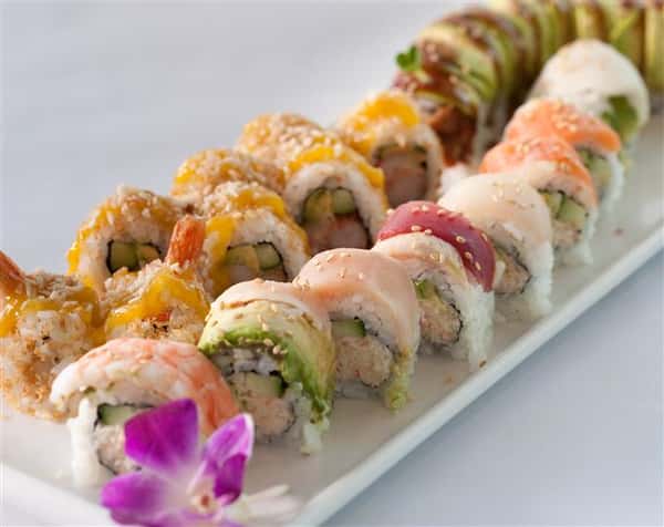 Sushi platter with a plethora of different sushi rolls served with a flower garnish