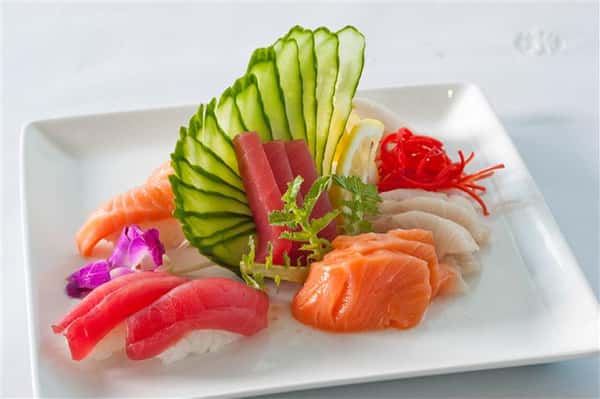 Sushi platter with a variety of different sushi served along with even cut veggies