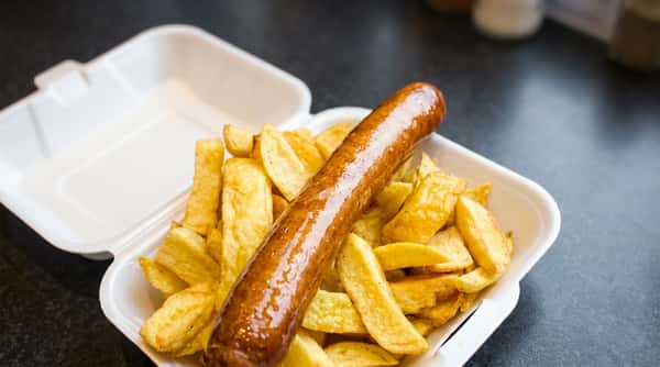 Large sausage served with freshly cooked chunky chips in a takeaway container.