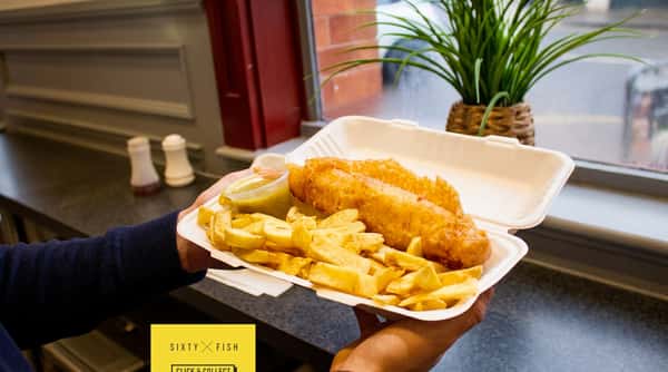 Freshly cooked battered fish and chunky chips presented in an open takeaway box.