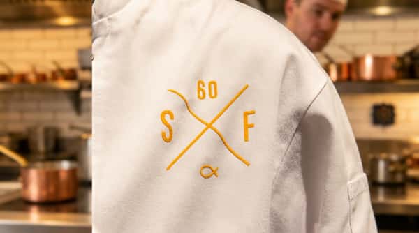 Close-up of a Sixty Fish staff uniform featuring the restaurant's embroidered logo.