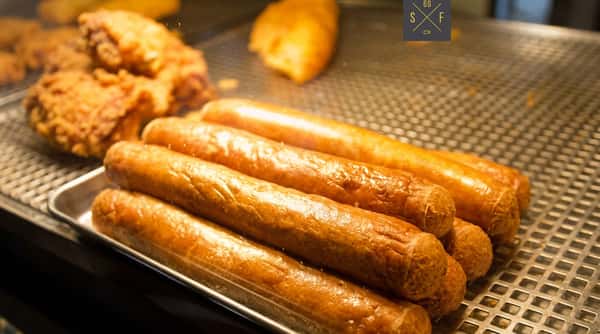Freshly cooked golden sausages displayed together at the fish and chip shop.