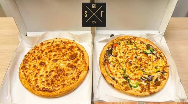 Two freshly baked pizzas, including cheese and vegetable toppings, presented in open boxes.
