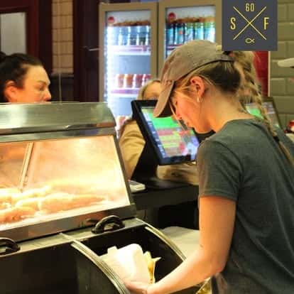Sixty Fish team member serving a customer at the takeaway counter in Coleshill.