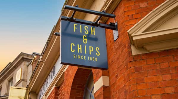 Traditional Sixty Fish hanging sign advertising fish and chips outside the Coleshill shop.