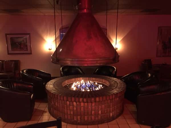 six leather chairs arranged in a half-circle around a circular fireplace
