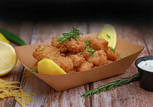 Delicious crispy fried shrimp served with fresh lemon and herbs on a rustic wooden table.
