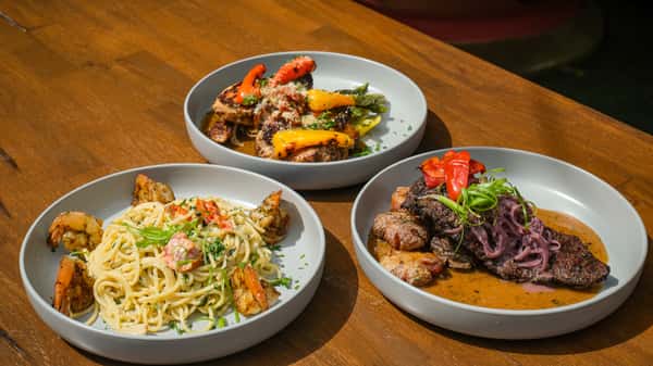 Chef-crafted dinner entrées featuring grilled steak, seafood pasta and seasonal vegetables, presented as an upscale restaurant dining experience.