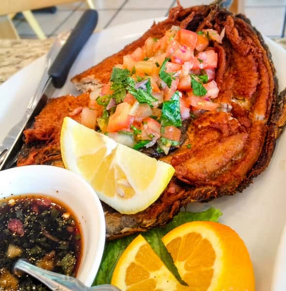 Crispy fried whole fish topped with fresh tomato salsa, served with citrus slices and savory dipping sauce.