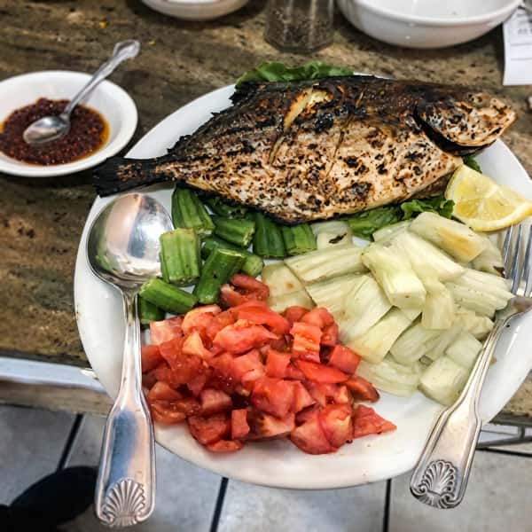 Perfectly grilled fish served with fresh vegetables and flavorful dipping sauces.