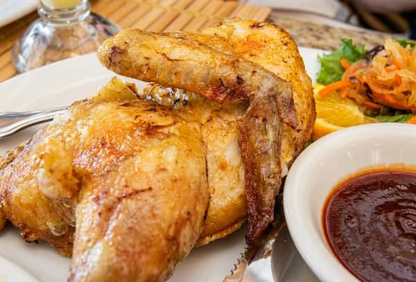 Golden roasted chicken with crispy skin, served juicy and flavorful with a savory dipping sauce.