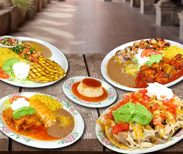 A spread of authentic Mexican dishes arranged on a wooden table, featuring enchiladas, rice, beans, guacamole, and fresh garnishes. Each plate is rich in color and texture, showcasing generous portions and traditional flavors, perfect for sharing in a warm, inviting dining setting.