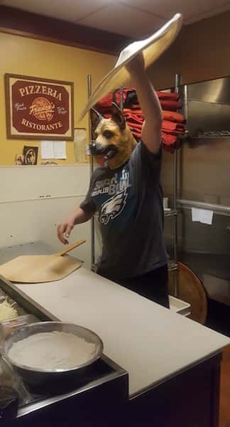 staff member with dog mask tossing pizza dough
