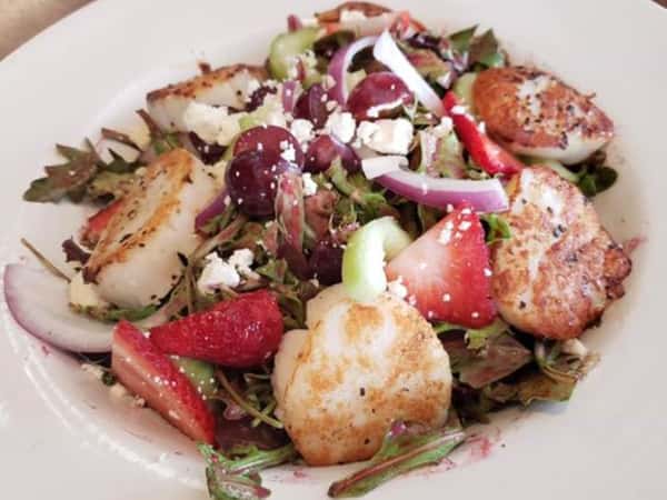 grilled scallop salad topped with onions, grapes, and strawberries