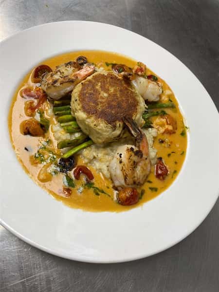 grilled shrimp with a crab cake over a bed of asparagus