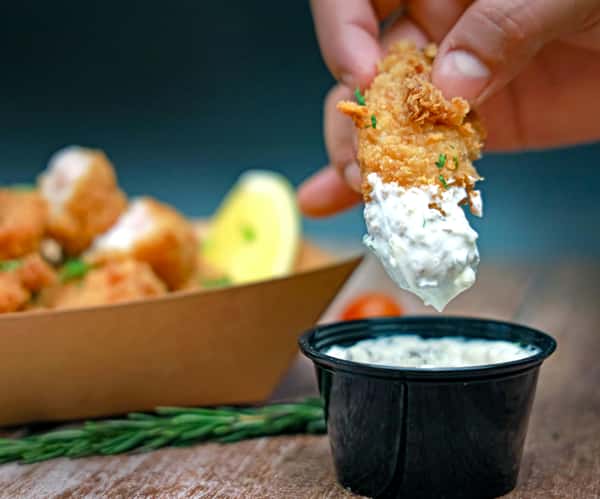 Delicious golden fried fish dipped in creamy sauce, perfect for seafood lovers.